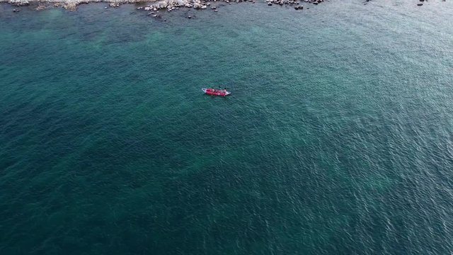 Inflatable open kayak paddlers explore near shore in clear green water