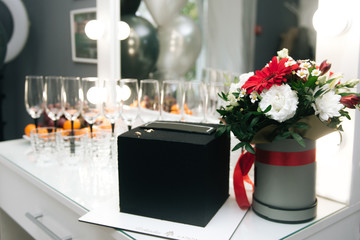 Stylish black cake with free space on the background of glasses and flowers. The concept of the Banquet and celebration