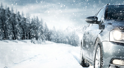 Gray winter car on road with snow.Free space for your decoration.Snowflakes and forest of frost.Cold december day. 