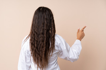 Young woman over isolated background pointing back with the index finger