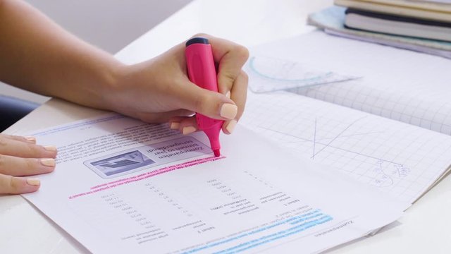 Left-handed Girl Using A Pink Marker In Highlighting Her Homework - Close-up Shot
