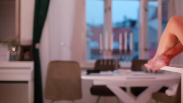 A girl in a bra and panties sits on a table at a party.