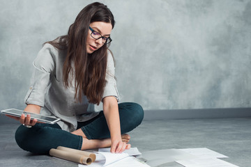 young female freelancer and entrepreneur is working on a project sitting on the floor.