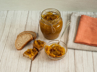 Indian cuisine, popular in England. Chutney is made from apples, raisins and spices. A can of chutney, whole grain bread, linen napkins on a light wooden background..