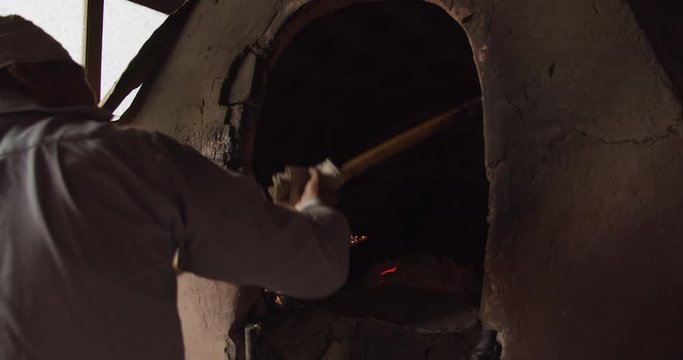 A man lays a lepeshka bread in a tandoor stove. Margilan city, Uzbekistan, Central Asia