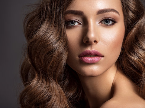 Beautiful woman with brown hair. Beautiful face of an attractive model with fashion makeup.