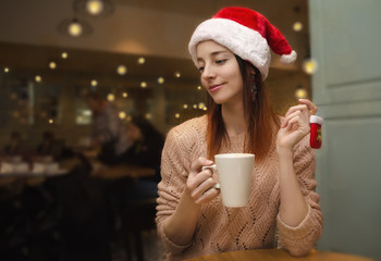 Pensive girl drinks coffee in a coffee shop at Christmas