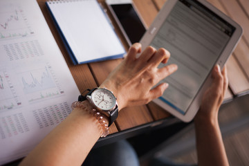 Women's hands with neat manicure and large wristwatch, work with gadgets, tablet, smartphone,...