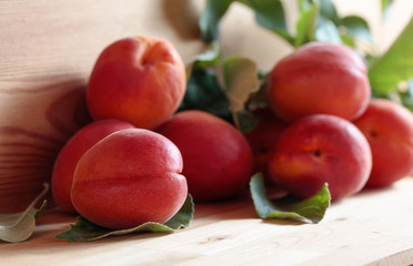 Apricots with leaves on a wooden table.