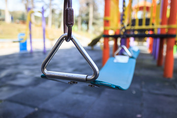 Blue empty child swing seat in a colorful play park, close-up with blurred background. Concept, arrangement of a children's playground.