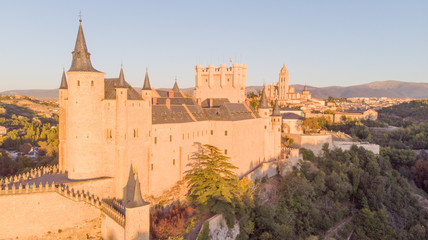 Obraz premium Historic medieval Castle in Segovia, Spain. Drone aerial view with sunset light of spanish stronghold in old town with monument cathedral. History prison, alcazar of Segovia, world heritage.
