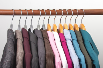 Different women's office classic jackets and shirts hang on a hanger for storing clothes. The choice of style of fashionable clothes