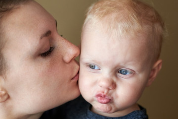 Mom kisses her little son, portrait, close-up.
