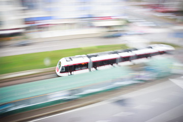 Fototapeta premium Fast moving blurred tram approaching to train station in city landscape. Light rail system in city.