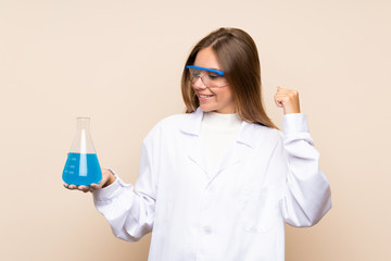 Young blonde woman over isolated background with a scientific test tube and celebration