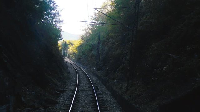 View over a single railroad track leading into a railway tunnel through the mountains of Romania