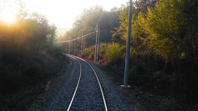 View over a single railroad track in the mountain and forested area in Bulgaria during golden hour