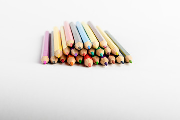 Group of mixed colourful pencils isolated on white, children school or office suppliers photographed from side view with space for text