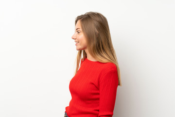 Young blonde woman with red sweater over isolated white background looking to the side