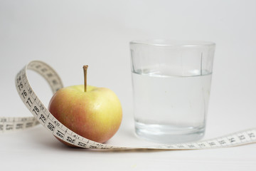 Healthy lifestyle concept. Apple and meter with a glass of water, representing healthy nutrition and diet concept isolated on gray background.