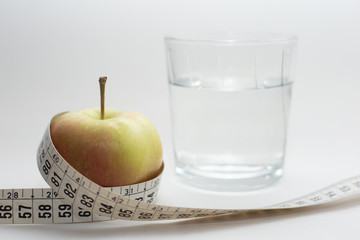 Healthy lifestyle concept. Apple and meter with a glass of water, representing healthy nutrition and diet concept isolated on gray background.