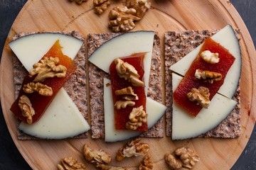 Wood plate with cheese, nuts and quince jelly on top of toasted bread. Healthy food. 