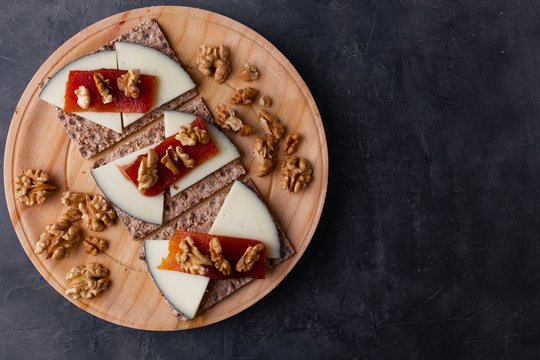 Wood plate with cheese, nuts and quince jelly on top of toasted bread. Healthy food. 