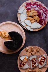 Variety of wood plates with freshly jamon, cheese and roasted bread; a whole cheese and toasted bread with cheese, nuts and quince jelly.