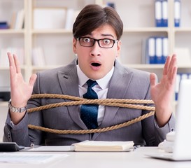 Businessman tied up with rope in office