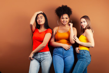 young pretty multiracial girls posing cheerful on brown background, lifestyle people concept