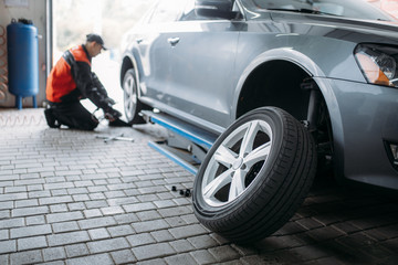 Repairman with pneumatic wrench unscrews the wheel