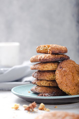 Homemade organic oatmeal cookies with peanuts  and bottle of milk on light concrete background.