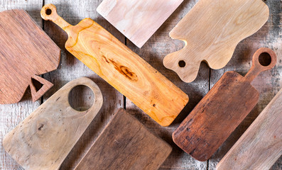 Top view of set of variety of handmade DIY wooden cutting board on old rustic wooden background.