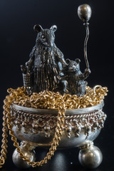 Composition from metal figures from gold and silver. Mom rat and baby on a pot of chains. Concept of the year 2020 on the eastern calendar. Symbol of wealth and family well-being Black background