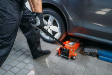 Auto mechanic jacks the car in tire service