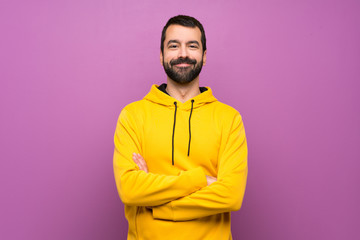 Handsome man with yellow sweatshirt keeping the arms crossed in frontal position