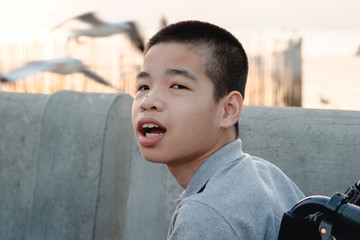 Portrait of Disabled child on wheelchair, Public bridge background with blurry, Special children’s enjoying outdoor activity at a normal life,Life in the education age ,Happy disability kid concept.