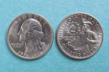 American US coins lie on a light blue background. Denomination: 25 cents, quarter, drummer, 1976. Both sides: obverse and reverse. XF condition. Declaration of Independence. View from above. Macro