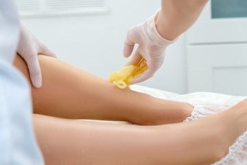 Obraz na płótnie Canvas beautician hair removal procedure on the client's feet in beauty parlor