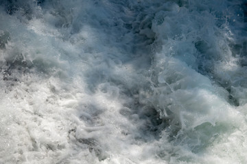 Naklejka na ściany i meble Closeup of flowing water and spray in river with sunlight for background, copy space and wallpaper