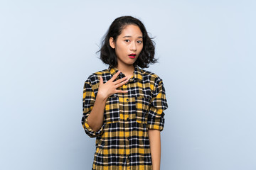 Asian young woman over isolated blue background surprised and shocked while looking right