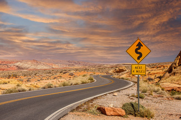 A road sign in the middle of a desert showing curves ahead