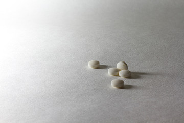 Fototapeta na wymiar Closeup white little many pills on white light table background.