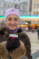 Happy laughing woman. Beautiful woman in winter clothes with coffee in hand On the background of beautiful bokeh. outdoor. vertical photo