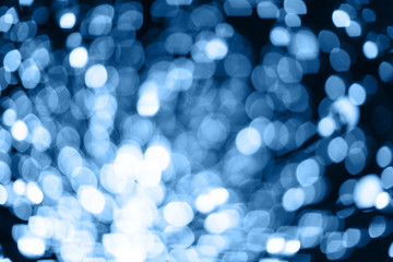 Fototapeta na wymiar Abstract blurred background with numerous bright festive bokeh in trendy Classic Blue color of the year 2020. Celebration, holidays concept. Horizontal. For lifestyle blog, social media