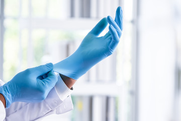 The scientist Wearing blue rubber gloves before experimenting in the laboratory with blur background