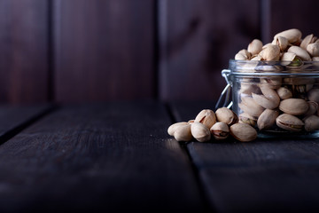 Pistachios in glass jars on a wooden background