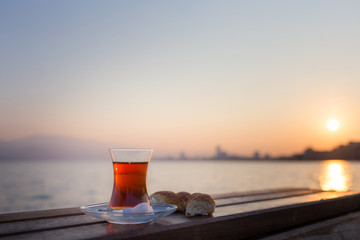 tea in traditional turkish glass and turkish bagel simit at dawn against the backdrop of the gulf of Izmir