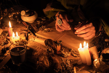Hands fortune teller over an ancient table with herbs and books. Manifestation of occultism in the...