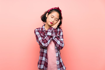 Asian young woman over isolated pink background making sleep gesture in dorable expression